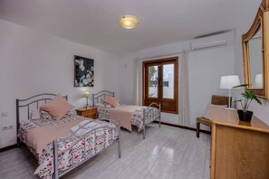 A bedroom with two beds, a wooden desk, a chair, a potted plant, and a window with curtains. - 3 Bedroom Villa with Air Conditioning, Parking and Pool (Tías)