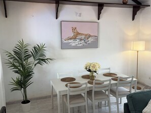 A dining area with a white table, woven placemats, and chairs. A framed picture of a leopard is on the wall. - 3 Bedroom Villa with Air Conditioning, Parking and Pool (Tías)