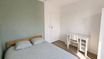 Un dormitorio con cama, escritorio y puerta.