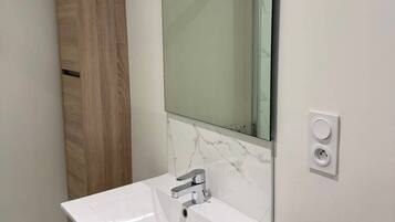 A bathroom with a white sink, a wooden cabinet, and a mirror.