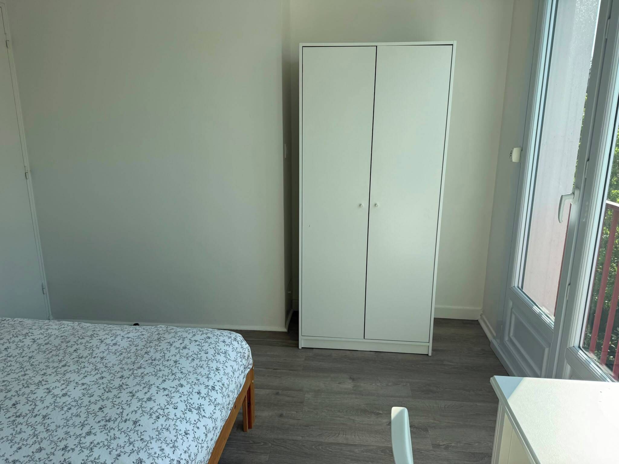 Ein Schlafzimmer mit Bett, Kleiderschrank und Fenster.