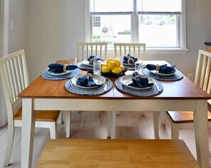 A dining table set for six with blue napkins, plates, and glasses, and a bowl of lemons on the table. - Raynor Shine | Walk to Beach | Family Fun | Dog Friendly (Falmouth)