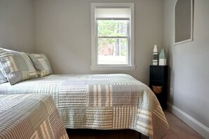 A bedroom with a bed, a window, and a nightstand. - Raynor Shine | Walk to Beach | Family Fun | Dog Friendly (Falmouth)