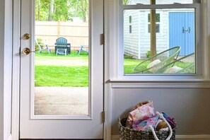 Une porte donnant sur un jardin, une porte bleue, et un panier en osier contenant divers objets.