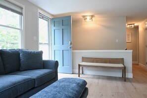 Una sala de estar con puerta azul, un banco y un sofá.