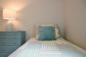 Un dormitorio con cama, mesita de noche y lámpara.