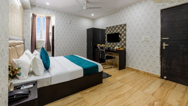 Un dormitorio con cama, escritorio, silla, televisor y una puerta.