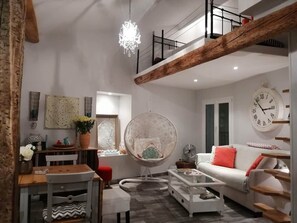 A spacious living area with a high ceiling, a dining table, a round chair, a sofa, and a clock on the wall. - Traverse du Vieux Château (Menton)