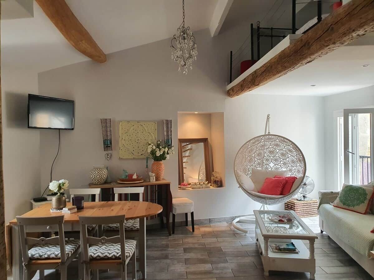 Ein modernes Wohnzimmer mit Essbereich, einem Hängekorbsessel und einem Fernseher.