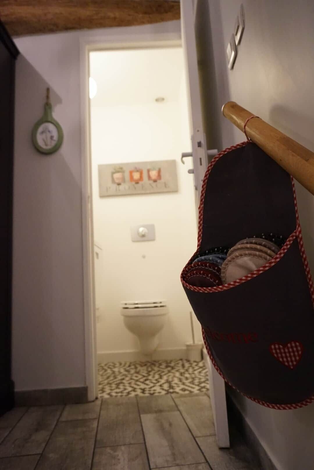 Een badkamer met toilet, handdoekhouder en een bord aan de muur.