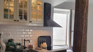 A kitchen with white cabinets, a black stove, and a window with a view. - Traverse du Vieux Château (Menton)