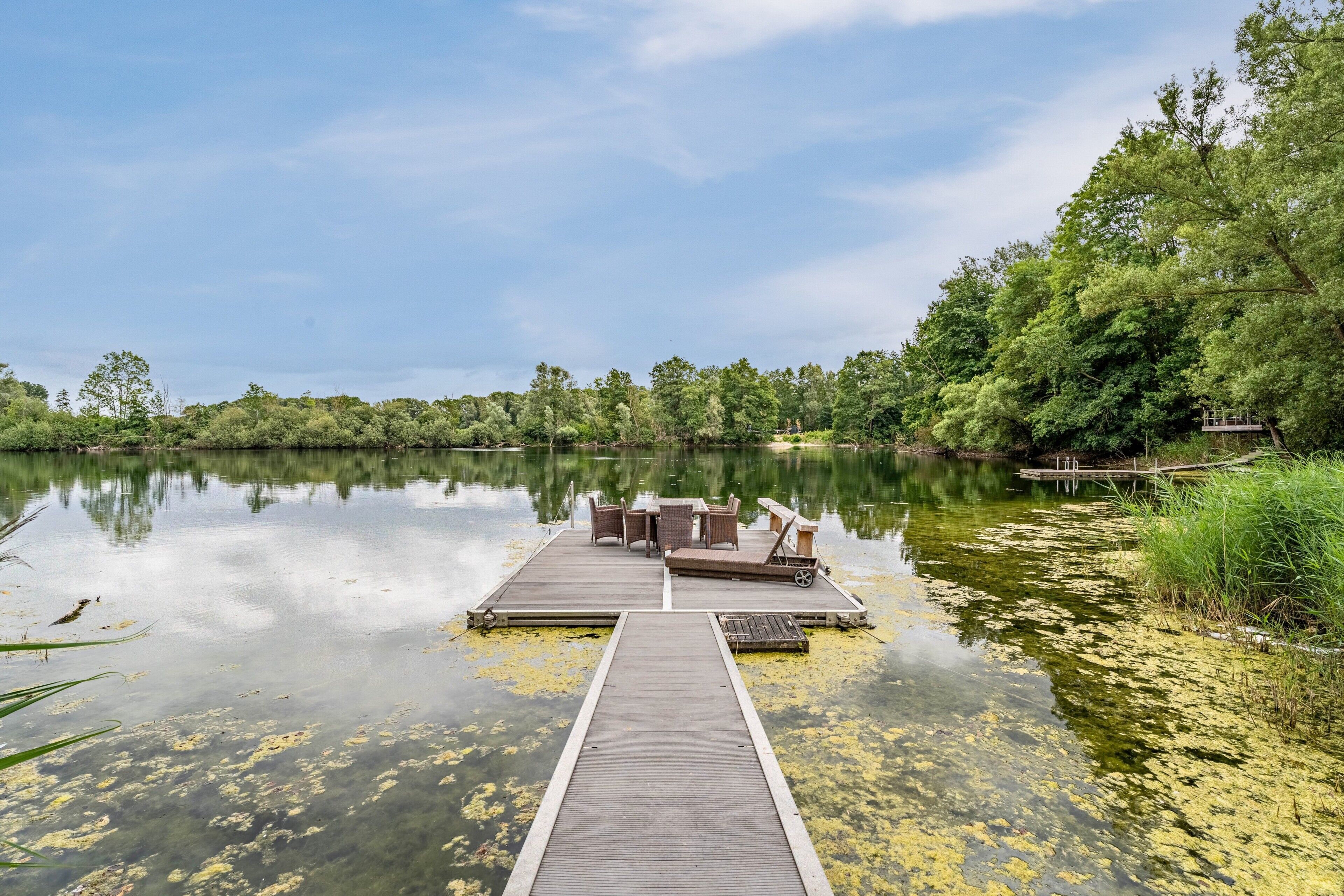 Une jetée en bois s’étendant sur un lac paisible, sous un ciel dégagé.