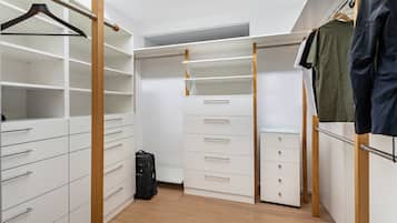 A walk-in closet with multiple drawers and shelves, a hanging rod, and a suitcase on the floor.
