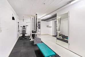 A gym with exercise equipment, a bench, and a large mirror.