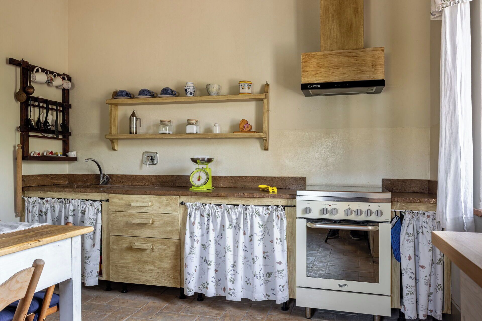 Une cuisine avec des meubles de rangement en bois, une cuisinière, un évier et un porte-casseroles suspendu.