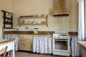 A kitchen with wooden cabinets, a stove, a sink, and a hanging pot rack.