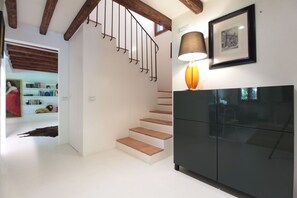 Una scala con gradini in legno e ringhiere in metallo, un armadietto nero con una lampada e un quadro appeso al muro.