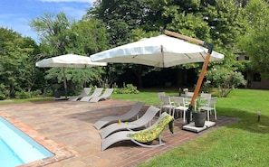 Eine Terrasse mit Liegestühlen, einem Pool und Sonnenschirmen.