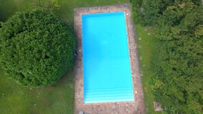 Vista aerea di una piscina rettangolare circondata da vegetazione lussureggiante.