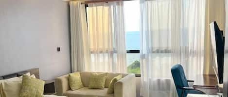 Habitación de hotel con cama, escritorio y silla. Se ve una ventana con cortinas.