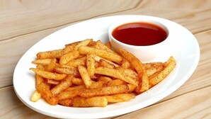 Ein weißer Teller mit gewürzten Pommes und einer kleinen Ketchup-Schale.