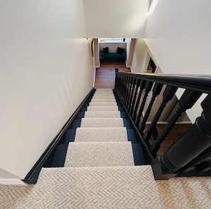A staircase with a carpeted landing and a black railing. - Lavender Cottage - Sleeps 12+ Hot Tub, Games Room, Pet Friendly (Burstwick)