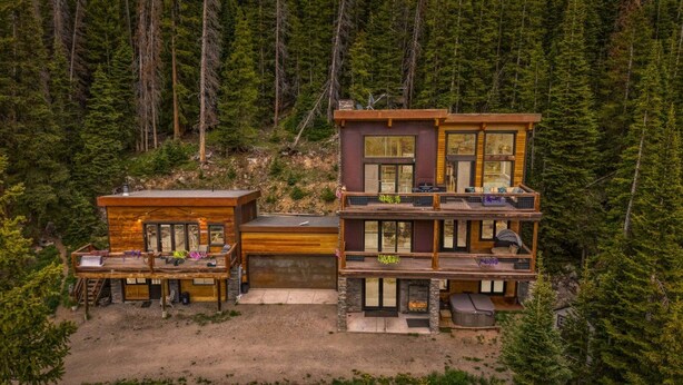 A multi-level cabin with a deck, surrounded by dense forest. - Stellar Peak Chalet 3 Bedroom Home (Montezuma)