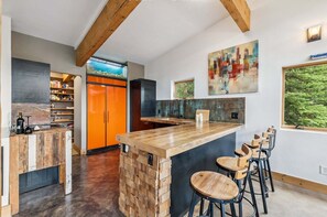 Eine moderne Küche mit einer Holzinsel, Barhocker und einem Stadtbildgemälde.
