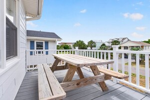 Una terraza de madera con una mesa de picnic y barandas blancas.