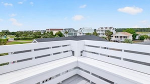 Un balcón blanco con vistas a edificios residenciales y un parque.