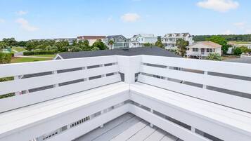 A white balcony with a view of residential buildings and a park.