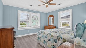 Un dormitorio con cama, cómoda, espejo y ventilador de techo.
