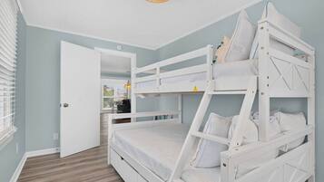A bunk bed room with a door, a window with blinds, and a hanging light fixture.