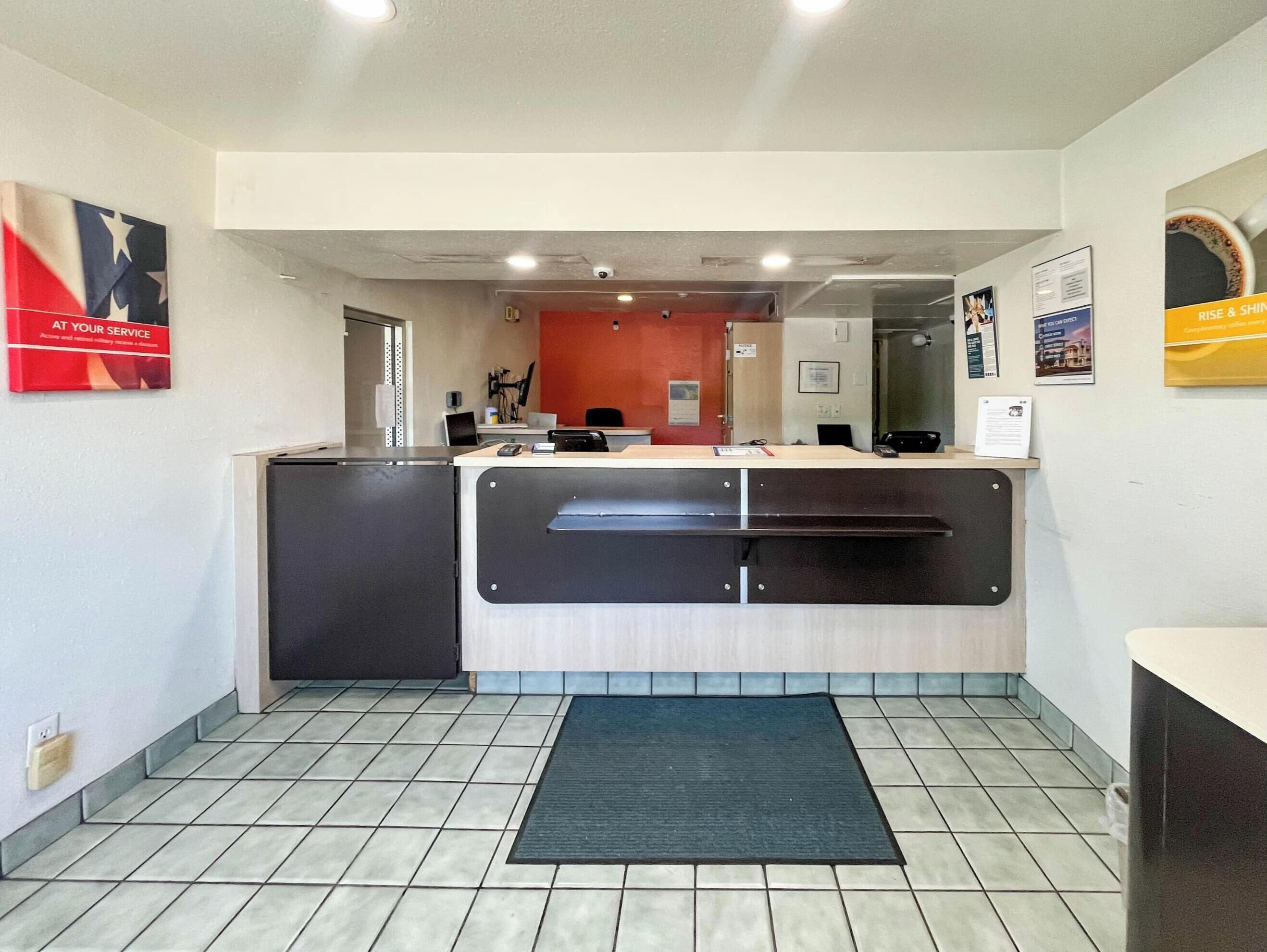 A reception area with a counter, a computer, and a door leading to another room.