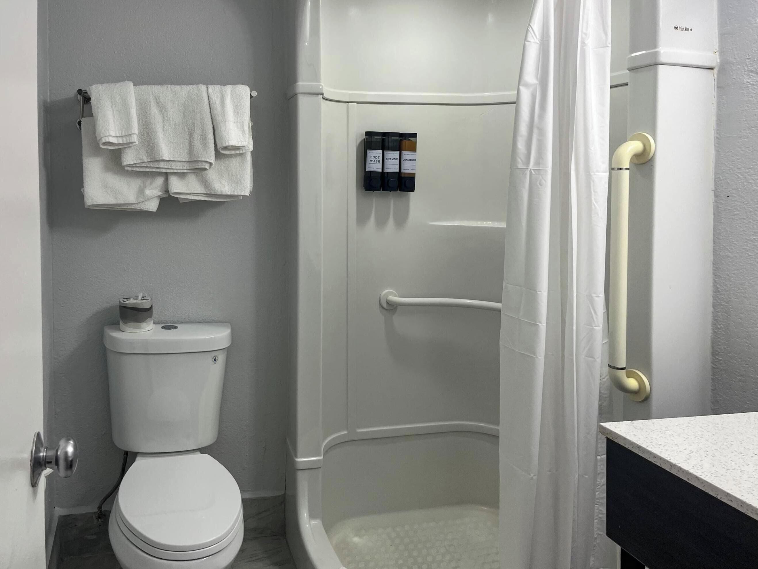 A bathroom with a toilet, a shower enclosure, and a towel rack with towels.