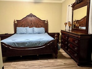 Ein Schlafzimmer mit einem hölzernen Bett, einem Schminktisch und einem Spiegel.