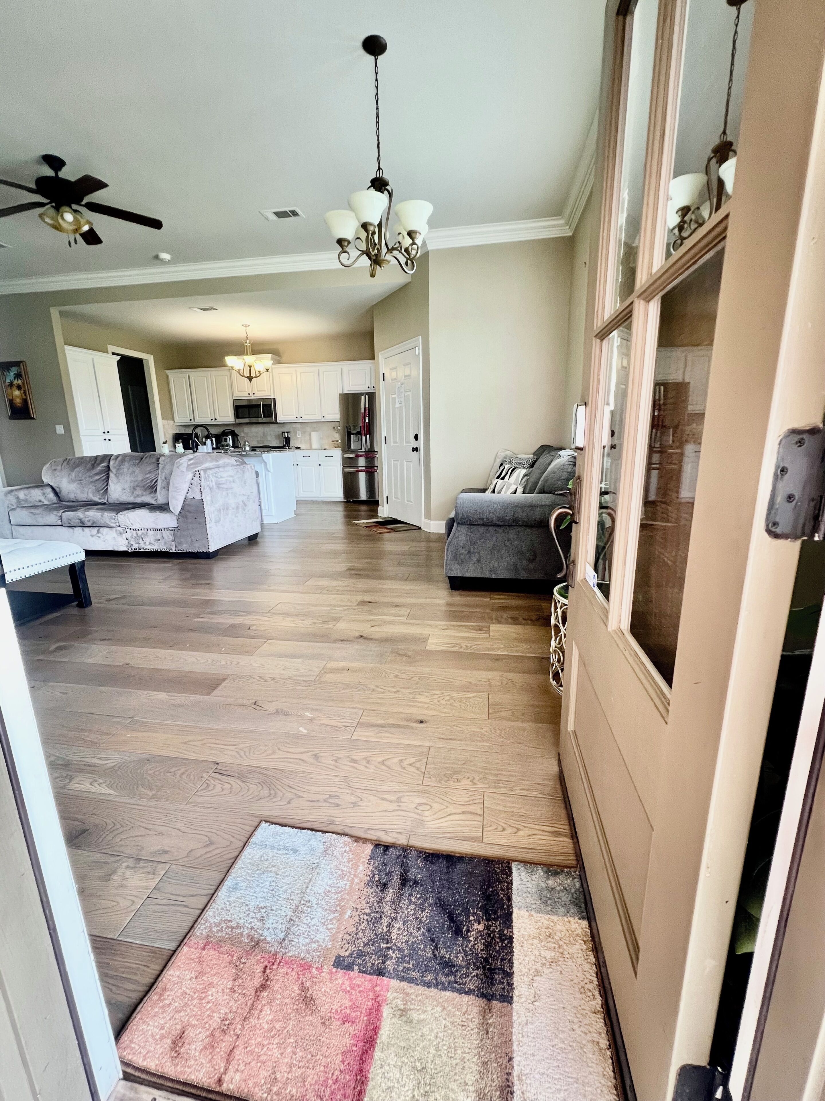 A spacious living area with a kitchen, a gray sofa, and a wooden floor.