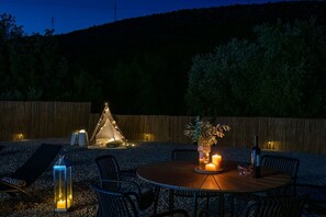 Ein Zelt, ein Tisch mit Kerzen und Stühle in einem Garten.