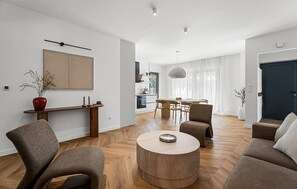 Un saló modern amb una taula de centre rodona de fusta, un sofà i una zona de menjador amb taula i cadires.