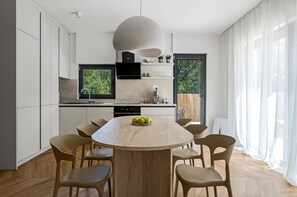 Una cuina moderna amb una illa central, armaris blancs i una finestra gran.