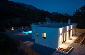 Ein modernes Haus mit Pool, einer überdachten Terrasse und Blick auf die Berge.