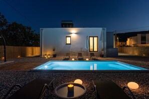A modern outdoor pool area with lounge chairs and a candle on a table. - Villa Three Olives: A Perfect Family Retreat near Omis (Naklice)