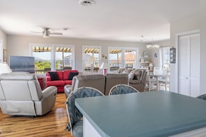 Un amplio espacio de estar con una gran mesa de comedor, diversas opciones de asientos y vistas al exterior.
