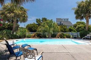 Una piscina con sillas de descanso y palmeras.