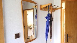 A mirror with a wooden frame, a coat rack with a blue umbrella, and a wooden door. - Charming vacation home in a stunning location right in the heart of Wingst (Wingst)