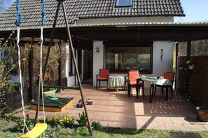 A patio with a swing set, outdoor seating, and a garden.