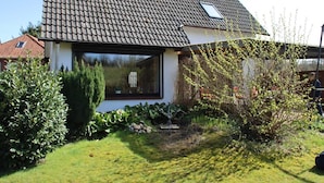 A house with a tiled roof, a large window, and a well-maintained garden with various plants and a small pond. - Charming vacation home in a stunning location right in the heart of Wingst (Wingst)