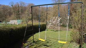 A swing set in a garden with a hedge, a ladder, and flowering trees. - Charming vacation home in a stunning location right in the heart of Wingst (Wingst)