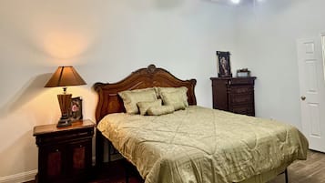 Une chambre à coucher comprenant un lit, une table de chevet, une lampe, une commode et un ventilateur de plafond.