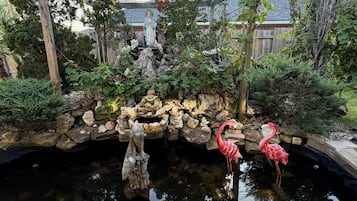 A garden with a pond, a statue, and two flamingos.
